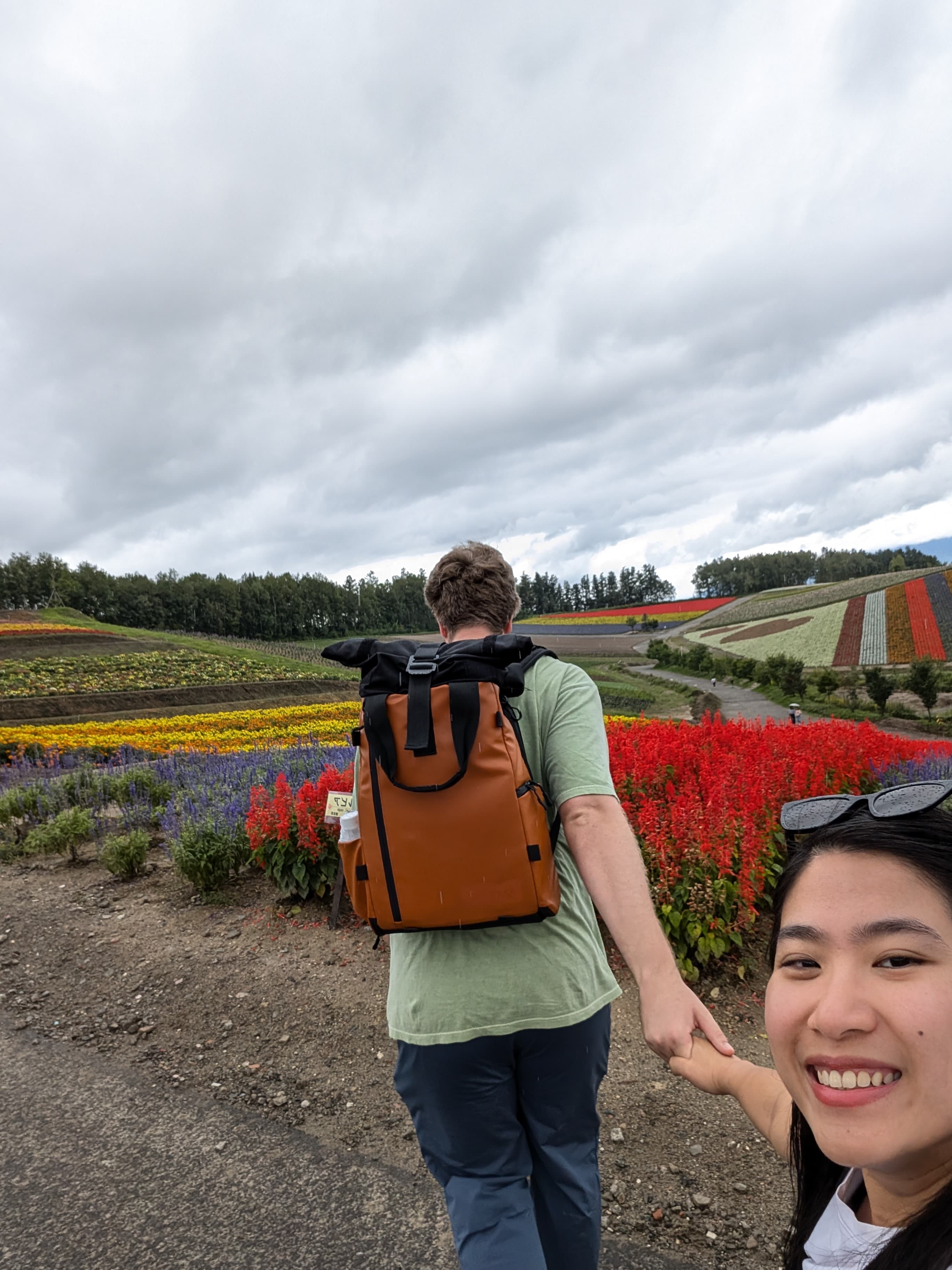 Couple walking hand-in-hand through golden flower fields in rural Victoria