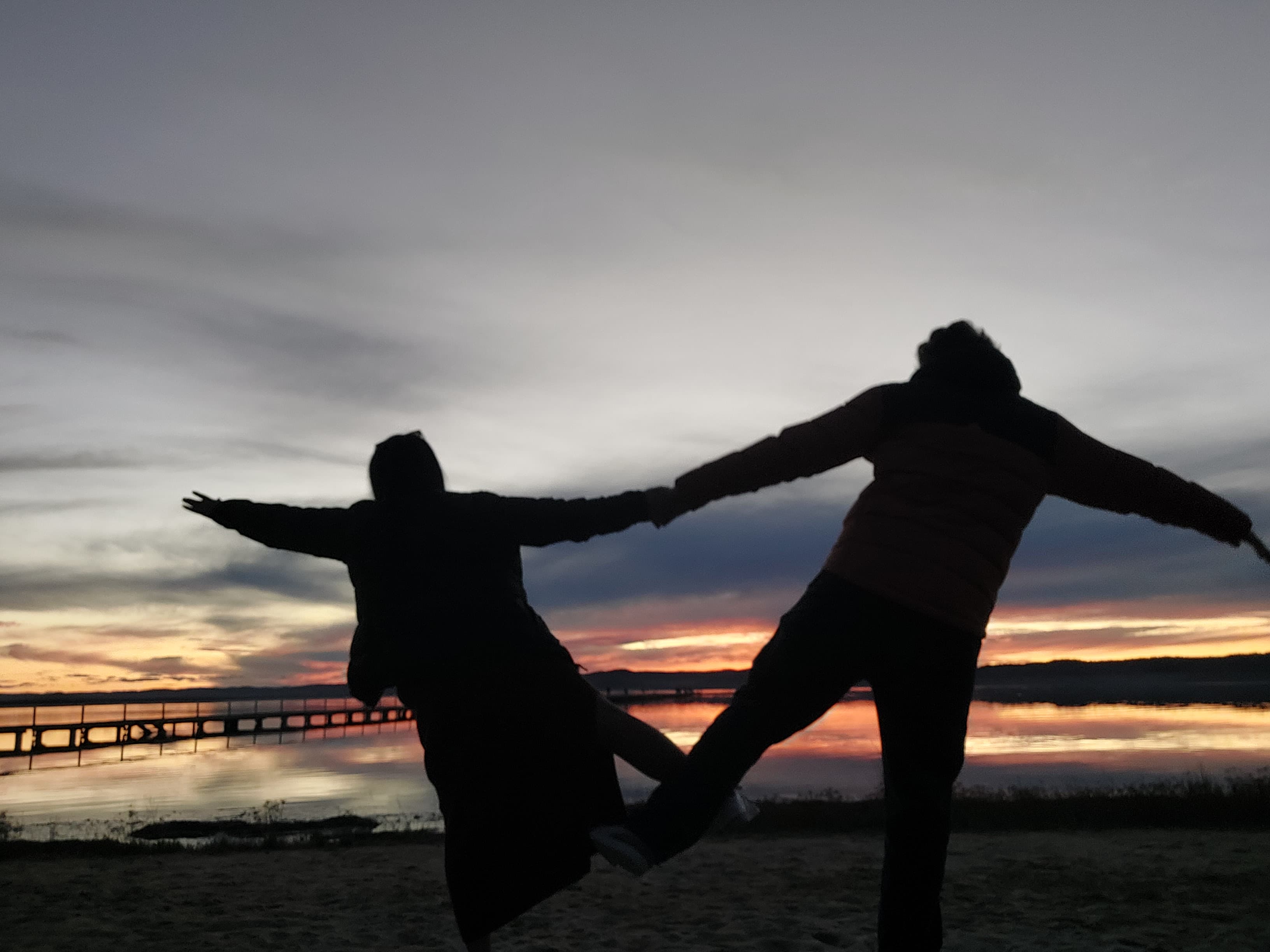 Silhouette of couple against a golden sunset on a pier